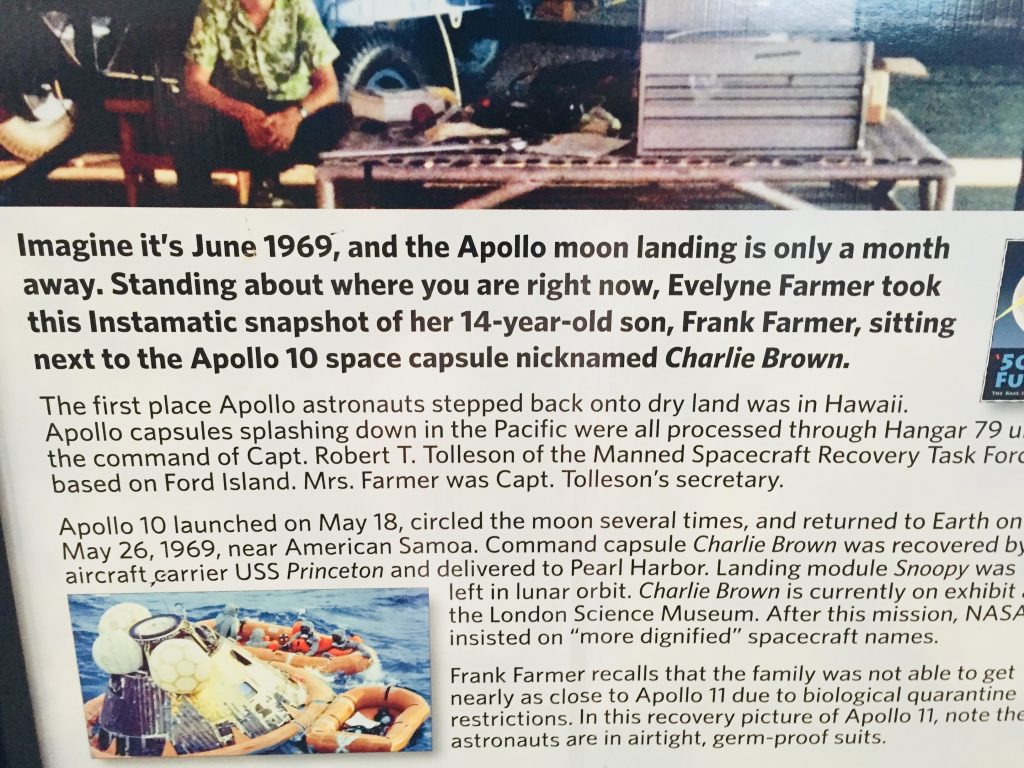 Apollo 10 was on Ford Island!
Imagine it's June 1969, and the Apollo moon landing is only a month away. Standing about where you are right now, Evelyne Farmer took this Instamatic snapshot of her 14-year-old son, Frank Farmer, sitting next to the Apollo 10 space capsule nicknamed Charlie Brown.
'50
FU
The first place Apollo astronauts stepped back onto dry land was in Hawaii. Apollo capsules splashing down in the Pacific were all processed through Hangar 79 u the command of Capt. Robert T. Tolleson of the Manned Spacecraft Recovery Task Forc based on Ford Island. Mrs. Farmer was Capt. Tolleson's secretary.
Apollo 10 launched on May 18, circled the moon several times, and returned to Earth on May 26, 1969, near American Samoa. Command capsule Charlie Brown was recovered by aircraft,carrier USS Princeton and delivered to Pearl Harbor. Landing module Snoopy was left in lunar orbit. Charlie Brown is currently on exhibit. the London Science Museum. After this mission, NASA insisted on "more dignified" spacecraft names.
Frank Farmer recalls that the family was not able to get nearly as close to Apollo 11 due to biological quarantine restrictions. In this recovery picture of Apollo 11, note the astronauts are in airtight, germ-proof suits.