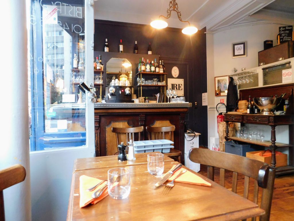 Bib Gourmand restaurant Bistrotters interior in Paris. Shows a table in the foreground and wine bottles in the background.