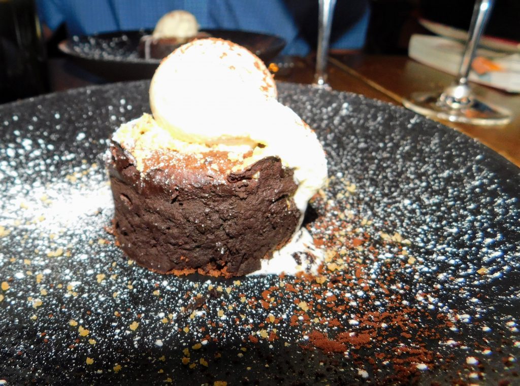 Lava cake with vanilla topping. The black plate has been sprinkled with powdered sugar and chocolate.
Dessert to die for at a Bib Gourmand restaurant (Bistrotters) in Paris