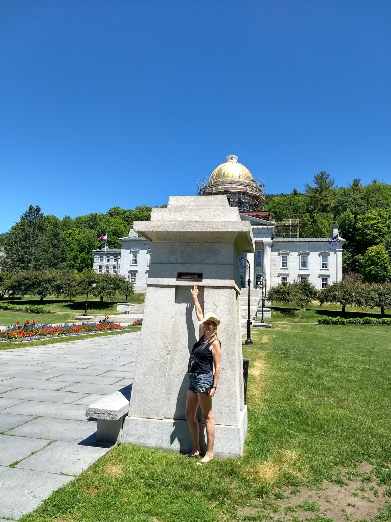 Karen in front of the Vermont statehouse pillar trying to reach the high water mark (1927)