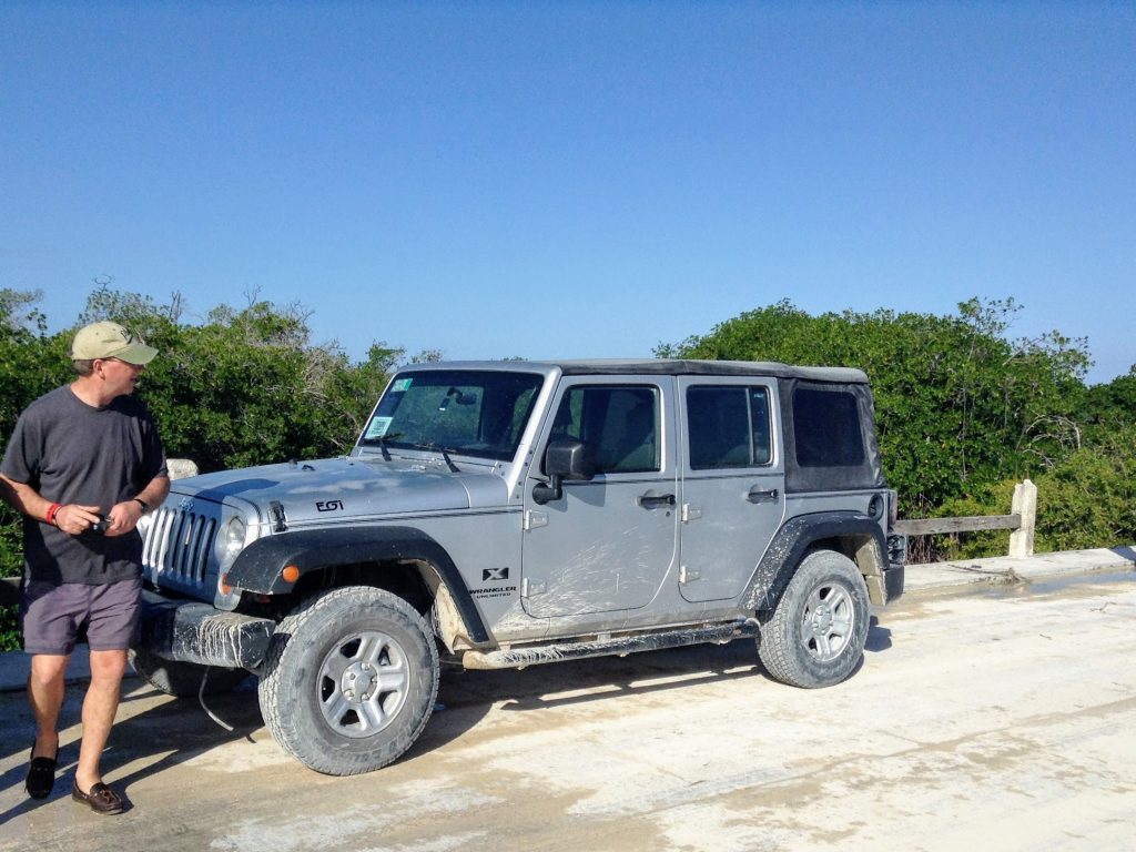 Jeep parked on the sand with Tom next to it