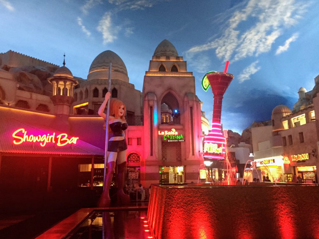 Showgirl bar sign with show girl with Arabian looking architecture in the back ground and a reflection lake on the right. Las Vegas can be overwhelming at time, find the best day trips to take a break from the sensory overload. 