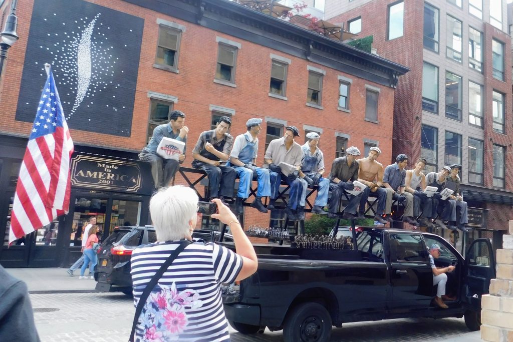 Quintessential New York City men on a steel beam on the back of a truck. 