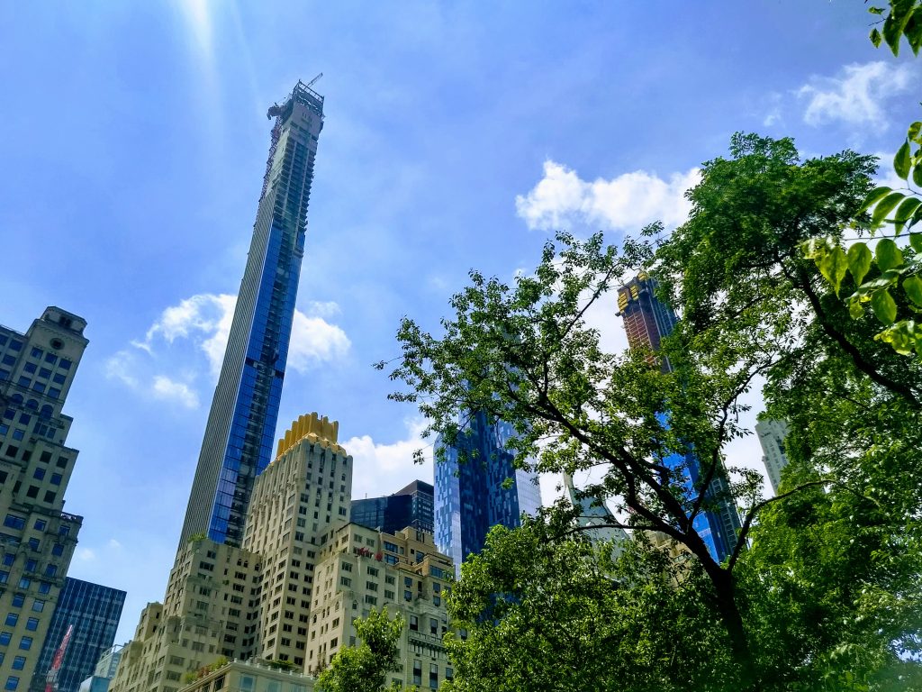 View towards Manhattan from Central Park. Trees in foreground, skyscrapers in background.