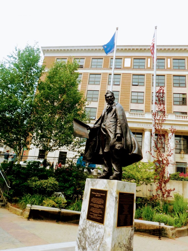 Statue and flags in front of the Alaska Capitol. Fun fact: it is one of the few capitol buildings without a dome