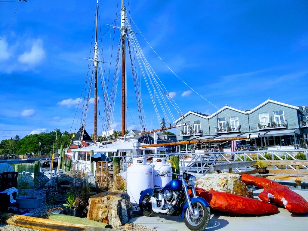 Harbor view in Kennebunkport with lobster, houses, blue motor cycle and sail boat. 