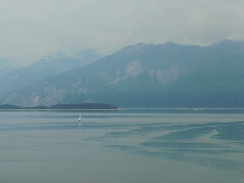 Tiny looking sail boat with Glacier Bay NP mountains in the background during our Holland-America Alaskan cruise