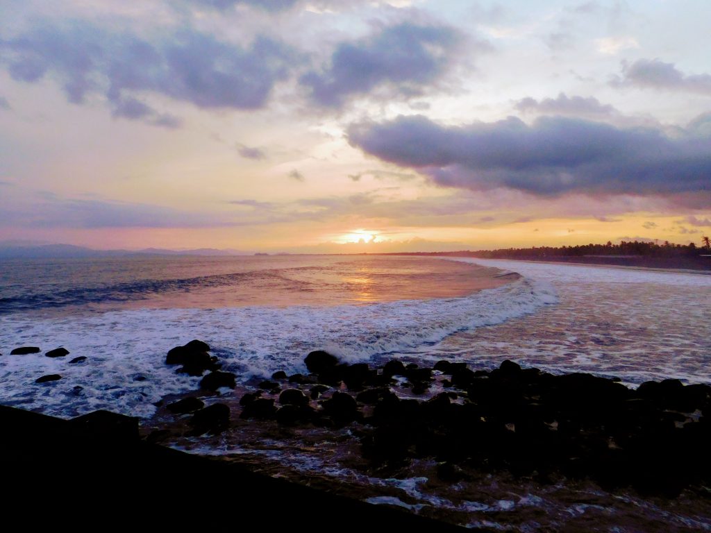 Sunset on our Costa Rica birding trip. Rocky beach in foreground, Setting sun and clouds in background. 