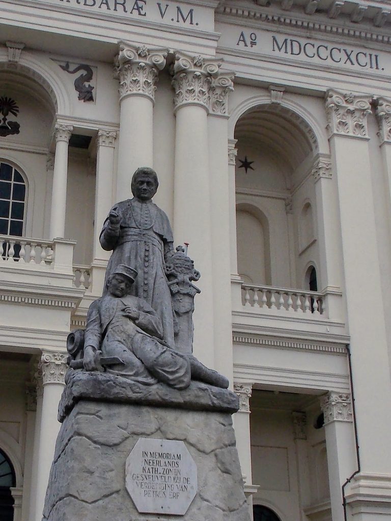 Statue of a fallen Dutch Zouave soldier being blessed by a priest in front of the The Oudenbosch Basilica