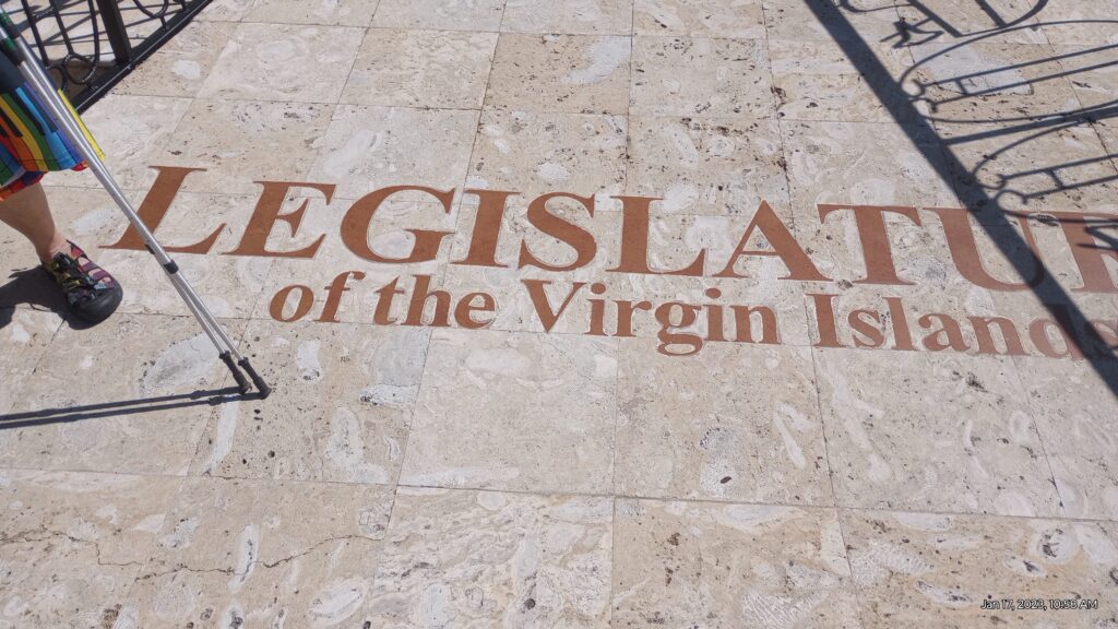 Legislature of the Virgin Islands with hiking poles, one foot and skirt with piano motif next to it.